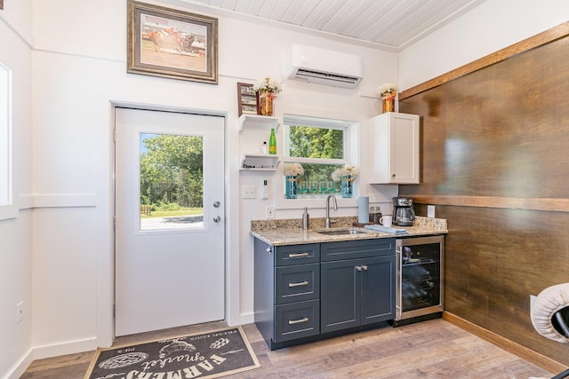 bar featuring sink, white cabinets, beverage cooler, light hardwood / wood-style floors, and a wall unit AC