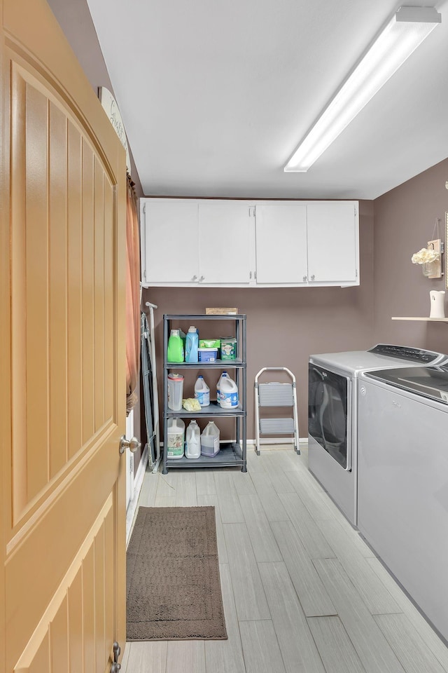 washroom with washer and clothes dryer and cabinets