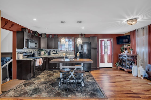 kitchen with pendant lighting, plenty of natural light, dark brown cabinets, and black appliances