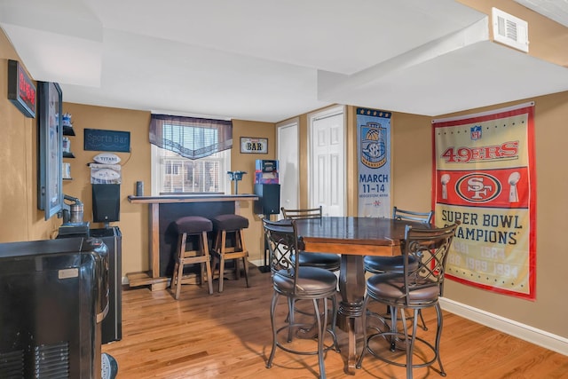 dining space featuring hardwood / wood-style flooring and bar area