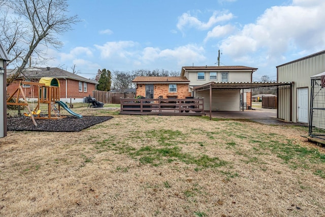 rear view of property featuring a playground, a yard, a deck, and a storage unit