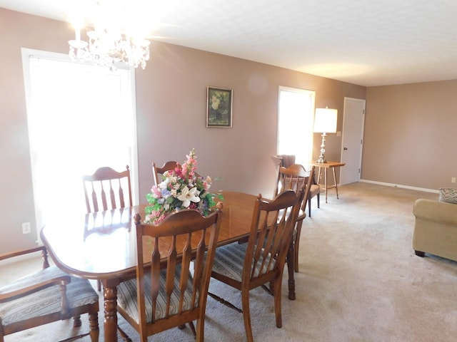 dining space featuring light colored carpet and a chandelier