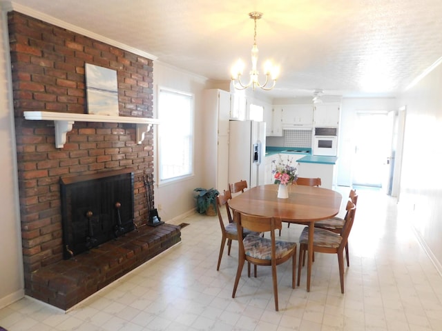 dining area featuring a notable chandelier, ornamental molding, and a brick fireplace