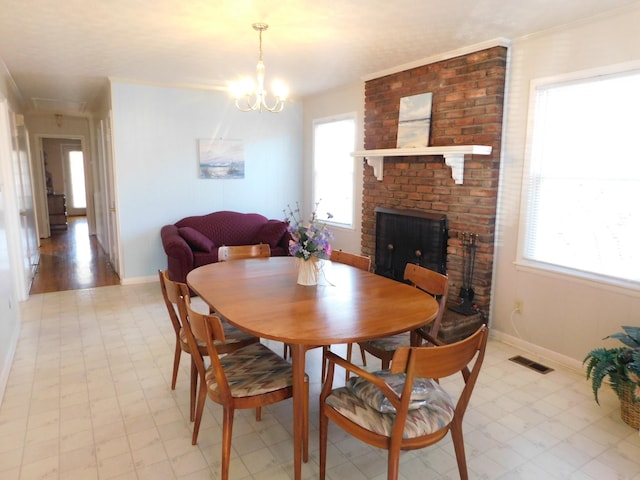 dining area with crown molding, a fireplace, and a notable chandelier