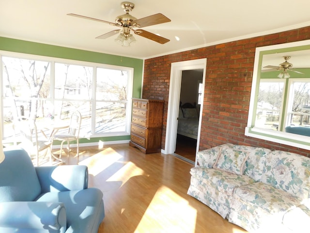 living room with ceiling fan, ornamental molding, brick wall, and hardwood / wood-style floors