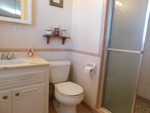 bathroom featuring tile walls, vanity, a shower with shower door, and toilet