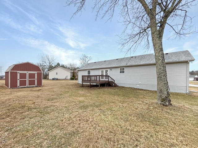 rear view of house with a lawn, a storage unit, and a deck