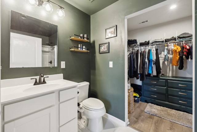 bathroom with vanity, hardwood / wood-style flooring, toilet, and walk in shower