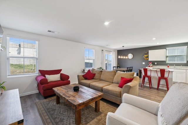 living room with a notable chandelier and dark wood-type flooring