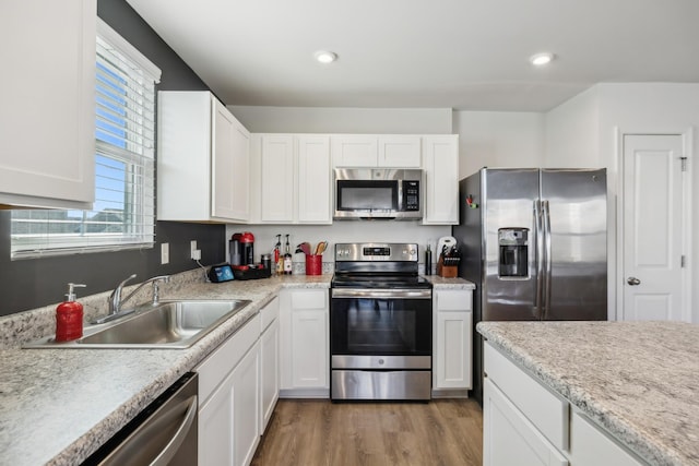 kitchen featuring sink, stainless steel appliances, hardwood / wood-style floors, and white cabinets