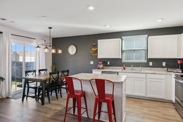 kitchen with pendant lighting, a center island, sink, and white cabinets