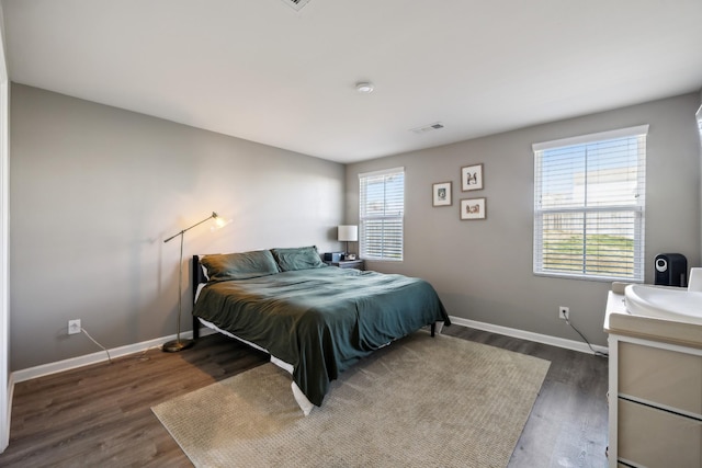 bedroom with multiple windows and dark hardwood / wood-style floors