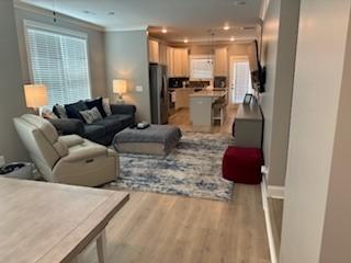 living room with crown molding and light wood-type flooring