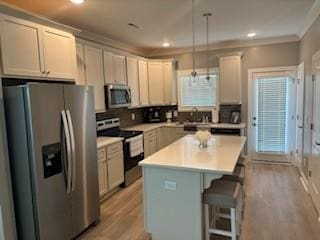 kitchen featuring a breakfast bar, hanging light fixtures, stainless steel appliances, a center island, and light wood-type flooring