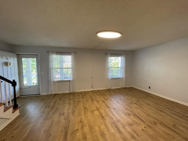 unfurnished room with wood-type flooring and a textured ceiling