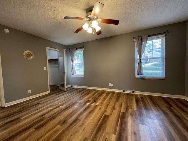 unfurnished room with dark wood-type flooring, ceiling fan, and a textured ceiling