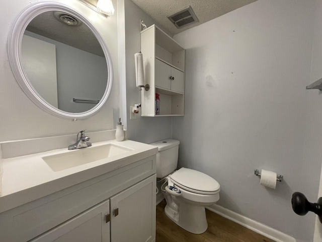 bathroom featuring wood-type flooring, vanity, a textured ceiling, and toilet