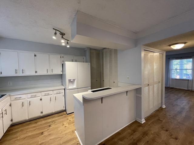 kitchen featuring white refrigerator with ice dispenser, a textured ceiling, white cabinets, and light wood-type flooring