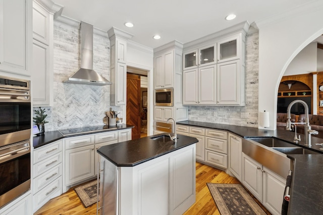 kitchen featuring built in microwave, white cabinetry, sink, and wall chimney exhaust hood