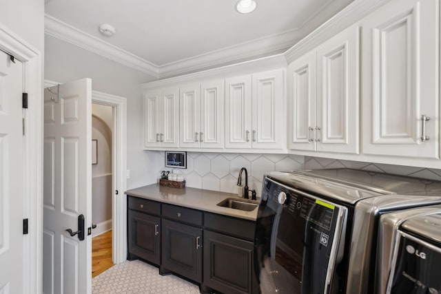 laundry room with separate washer and dryer, sink, ornamental molding, and cabinets