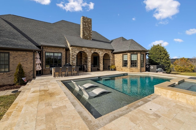 view of pool featuring a patio area, an outdoor bar, and an in ground hot tub