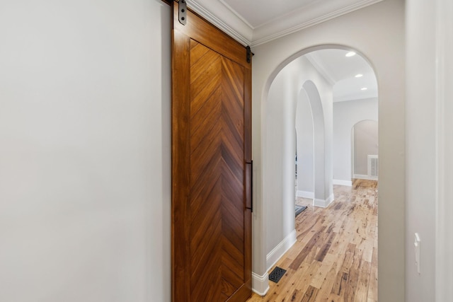 hall with crown molding, a barn door, and light hardwood / wood-style floors