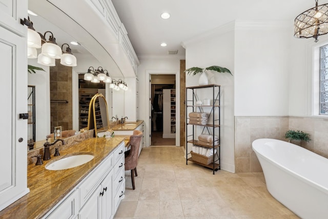 bathroom with tile walls, vanity, ornamental molding, tile patterned floors, and a bathing tub