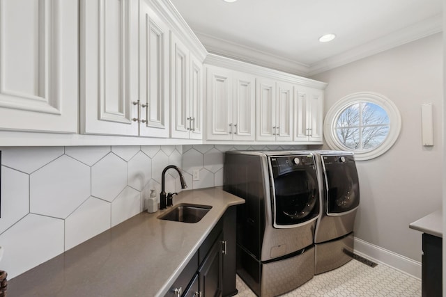 laundry area featuring cabinets, washing machine and dryer, sink, and ornamental molding