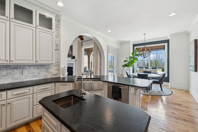 kitchen with sink, a kitchen island with sink, and light wood-type flooring