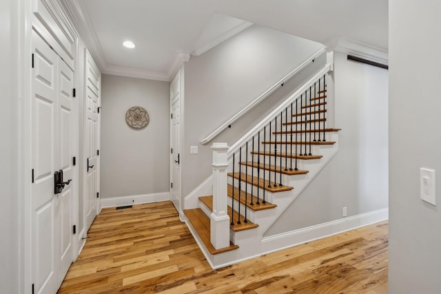 entryway with ornamental molding and light wood-type flooring