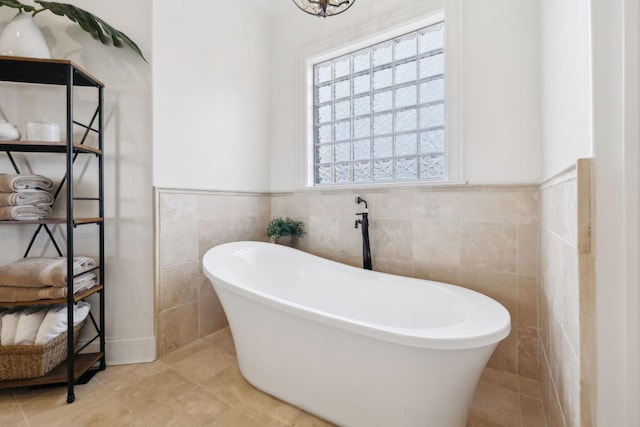 bathroom featuring a bath, tile patterned flooring, and tile walls