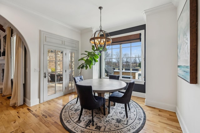 dining area with a notable chandelier, crown molding, and light hardwood / wood-style flooring