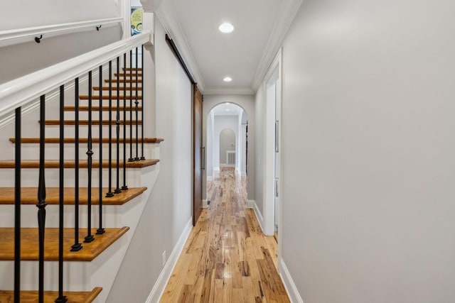 corridor with ornamental molding and light wood-type flooring