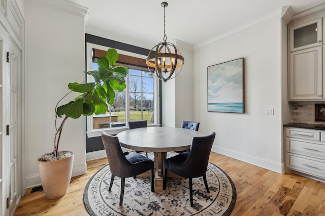 dining area featuring ornamental molding, an inviting chandelier, and light hardwood / wood-style floors