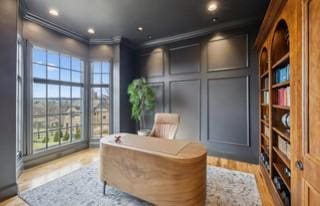 living area with crown molding and light wood-type flooring