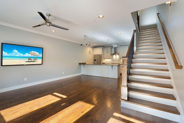 stairway with crown molding, sink, wood-type flooring, and ceiling fan with notable chandelier