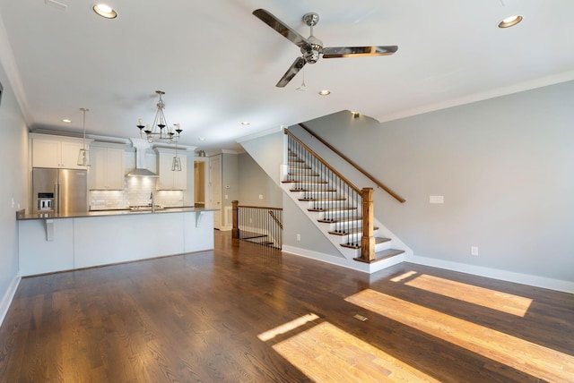 unfurnished living room with ornamental molding, sink, dark hardwood / wood-style floors, and ceiling fan with notable chandelier