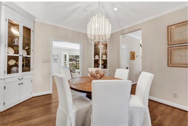 dining area with an inviting chandelier, crown molding, built in shelves, and hardwood / wood-style flooring