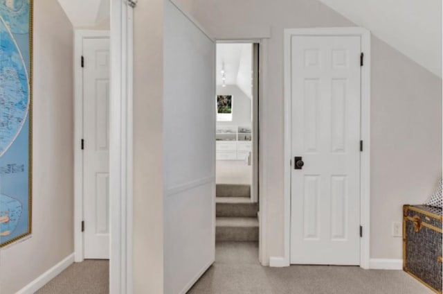 corridor featuring vaulted ceiling and light colored carpet