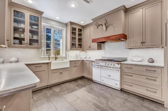 kitchen featuring sink, backsplash, and range with two ovens