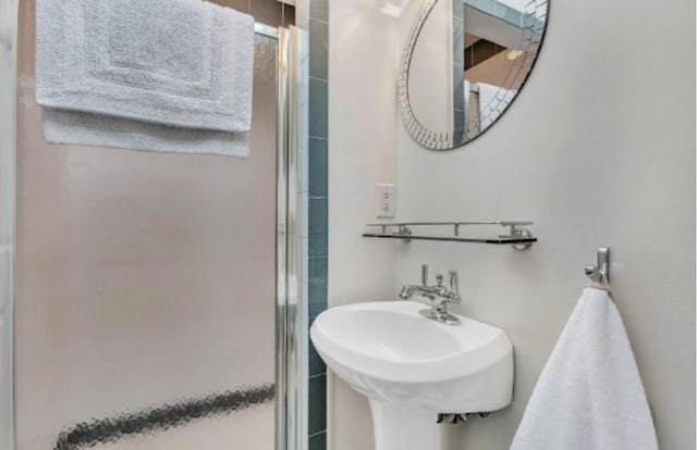 bathroom featuring sink and a shower with shower door