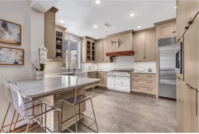 kitchen with a kitchen bar, stainless steel built in refrigerator, sink, kitchen peninsula, and backsplash