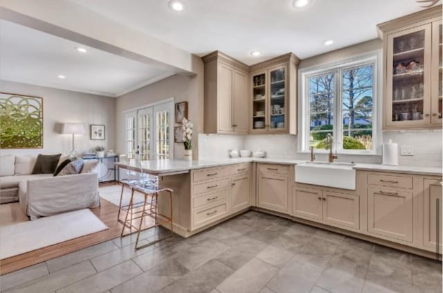 kitchen with sink, a breakfast bar area, backsplash, kitchen peninsula, and french doors