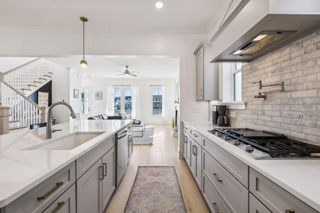 kitchen with gray cabinets, appliances with stainless steel finishes, pendant lighting, sink, and custom exhaust hood