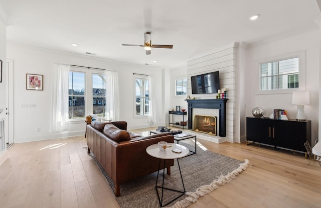 living room featuring crown molding, a brick fireplace, and light hardwood / wood-style flooring