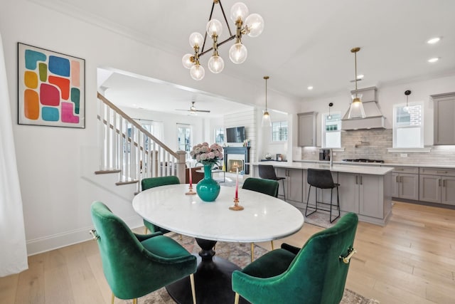 dining area with ornamental molding, sink, and light wood-type flooring