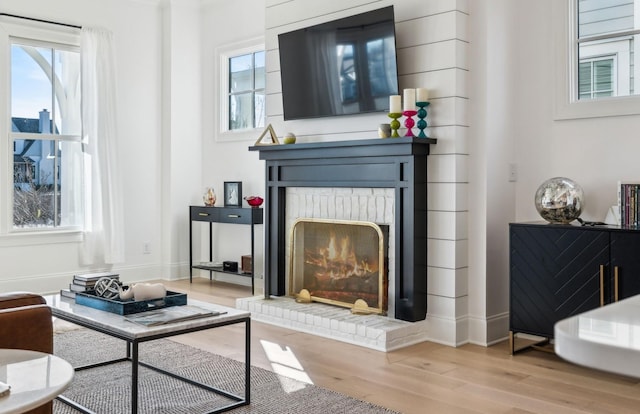 living room with a brick fireplace and light wood-type flooring