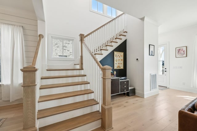 staircase featuring hardwood / wood-style flooring, a healthy amount of sunlight, and a high ceiling