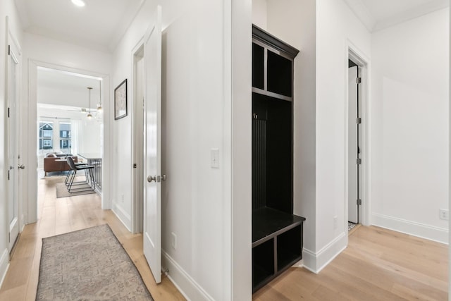 hall with ornamental molding and light wood-type flooring