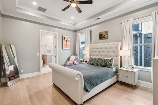 bedroom with crown molding, a tray ceiling, light hardwood / wood-style floors, and ceiling fan